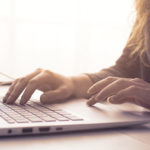 Woman sitting at desk and connecting with her laptop, she is working and typing on the keyboard, hands close up